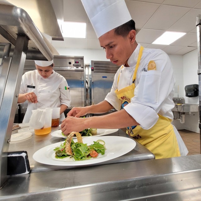 Spc. Noe Dominguez, a culinary specialist with 593rd Quartermaster Company, 548th Combat Sustainment Support Battalion, 10th Mountain Sustainment Brigade, works on precision plating of the salad during a run-through of the Student Chef menu. The team began training in May for the 2021 American Culinary Federation (ACF) National Competition in Orlando, Florida, Aug. 2-5. (Photo by Mike Strasser, Fort Drum Garrison Public Affairs)