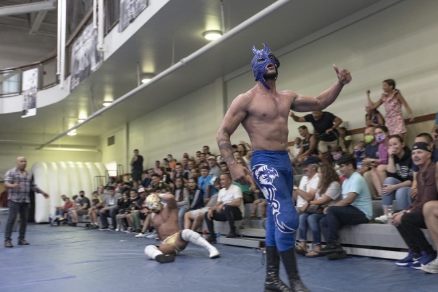 Luchadore El Dragon leaves dejected nemesis Sayrus in the dust during Lucha Libre wrestling at Fort Bliss, Texas, July 23, 2021. Bliss FMWR invited Lucha Frontera, a regional Lucha Libre wrestling production, on post for a free show for Bliss Soldiers, civilians, and their families and guests.
