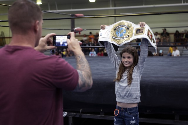 Army kid Olivia Whitehead, 10, grabs a photo opportunity from her photographer-dad, Master Sgt. David Whitehead, at the Lucha Libre wrestling event at Fort Bliss, Texas, July 23, 2021. Fort Bliss FMWR invited Lucha Frontera, a regional Lucha Libre wrestling production, on post for a free show for Bliss Soldiers, civilians, and their families and guests.