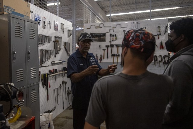 Donnie Brown with the Directorate of Family and Morale, Welfare and Recreations' Auto Craft Shop takes youths on a tour of the shop and shows them how to use the equipment during a teen drivers class July 16.
