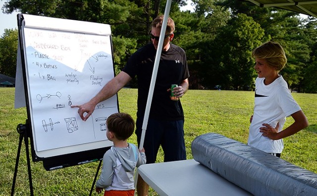 School of Advanced Military Studies student Maj. Brent Kinney shows his sons 4-year-old Rowan, 12-year-old Reid and 10-year-old Jackson, not pictured, the plans his Seminar 2 team made for their watercraft in the SAMS Boatyard Warz July 22 at...