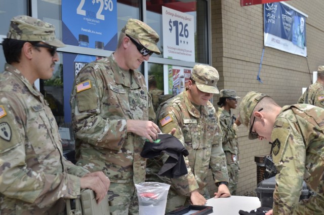 Specialist Carl West, 63rd Chemical Company (CBRN), receives a T-shirt from Staff Sgt. Russell Gore, 717th Ordnance Company, 184th Ordnance Battalion, 52nd Ordnance Group (Explosive Ordnance Disposal), after signing an interest form July 21 during...