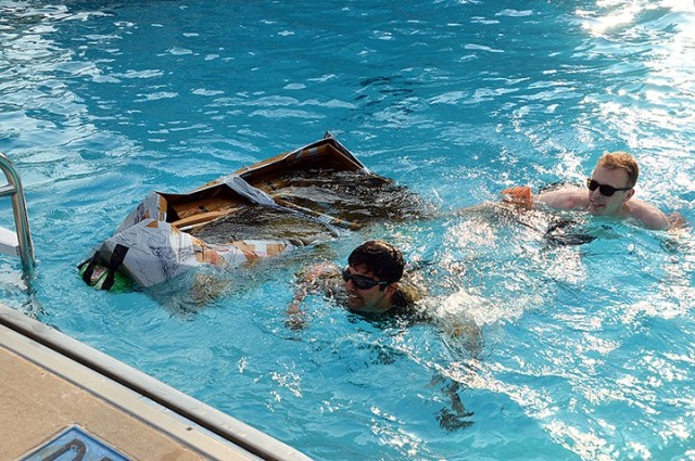 Seminar 5 competitors Pakistani Maj. Yasin Javed and Maj. Michael Pierri swim to the side of the pool as their boat sinks during the School of Advanced Military Studies Boatyard Warz heat 3 race July 22 at Hancock Pool. Photo by Prudence...