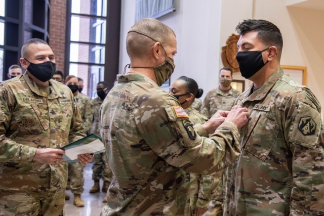 Sgt. Maj. of the Army Michael Grinston (center) assists with the promotion of Sgt. 1st Class Julio De La Cruz Feb. 9, 2021, in the foyer of the U.S. Army Military Police School command section. Grinston visited Fort Leonard Wood to engage with...