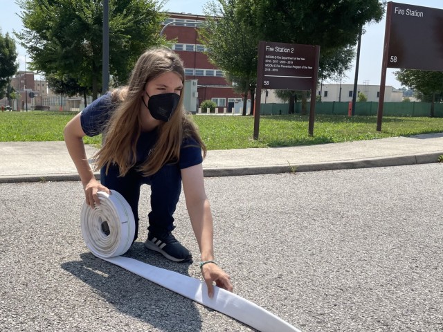 Charlie Wallace demonstrates the proper way to roll a fire hose, Vicenza, Italy, July 23, 2021. After being thrown into action, fire hoses are rolled up to ensure the removal of excess water.