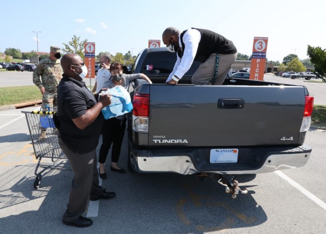Commissary employees load the store’s first CLICK2GO order into a vehicle parked in one of the designated service spots.