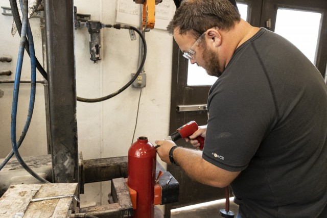 Jordan Goodwin, heavy mobile equipment leader, stamps the unique ANAD serial number and date on a fire bottle.