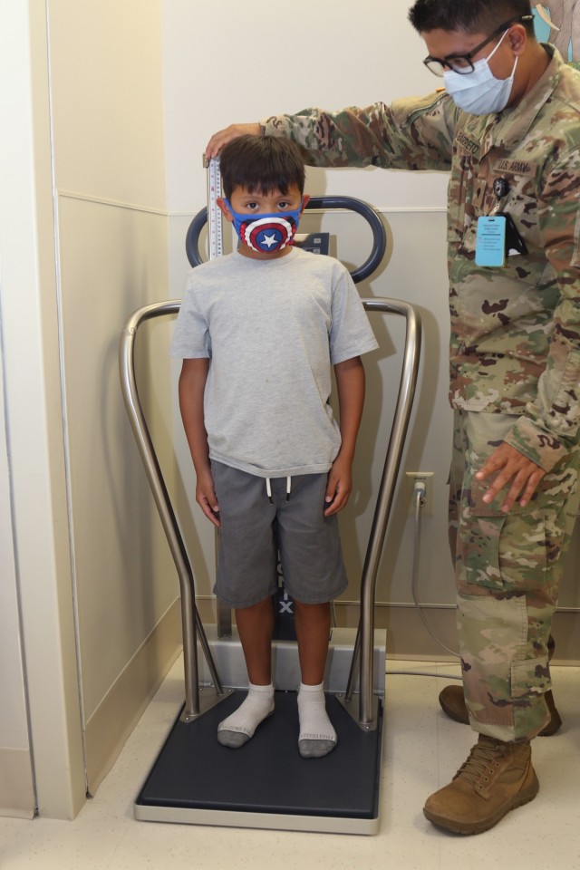 Spc. Jimmi Barreto (right), a surgical technician with Weed Army Community Hospital, measures the height of Nathan Garcia, 8, son of Jayme Mancera and Sgt. 1st Class Pablo Garcia, an observer, coach and trainer with Scorpion Team, Operations Group, July 29 during back-to-school physicals at Weed ACH, Fort Irwin, Calif.  (U.S. Army photo by Kimberly Hackbarth/ Weed ACH Public Affairs)