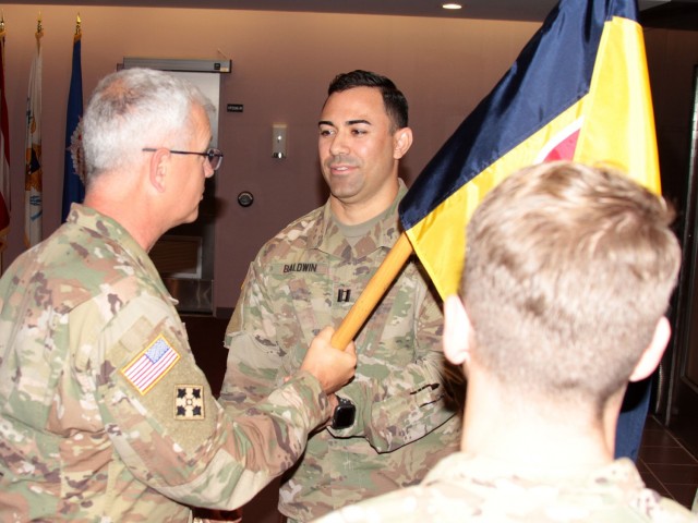 Col. Steven Carozza (left), U.S. Army Tank-automotive and Armaments Command chief of staff, passes the Headquarters and Headquarters Company guidon to Capt. Jose Baldwin, incoming HHC commander, at a Change of Command ceremony Jul. 23 at the Detroit Arsenal, Michigan. 