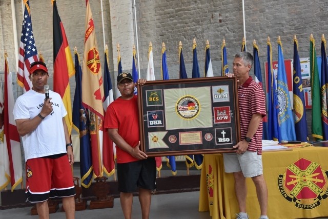 Col. Mario Washington, Garrison Wiesbaden commander, Mitchell Jones, deputy to the garrison commander and Garrison Command Sgt. Maj. Chris Truchon, show the plaque given to the command sergeant major for his goodbye from the Garrison.