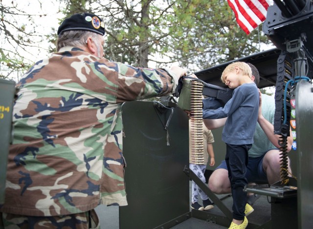 Steve Sumaral, a member of the Gamewarden of Vietnam Past to Present shows attendees the twin M2HB .50 caliber (12.7 mm) machine guns onboard a Navy Patrol Boat, River (PBR)  that was used during the Vietnam War. Sumaral is wearing a black beret,...