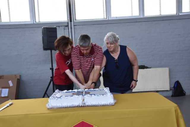 Command Sgt. Maj. Chris Truchon, his wife, Gwyn, and summer hire employee, Josh Kaiser, cut the goodbye cake for the command sergeant major at the Organization Day.