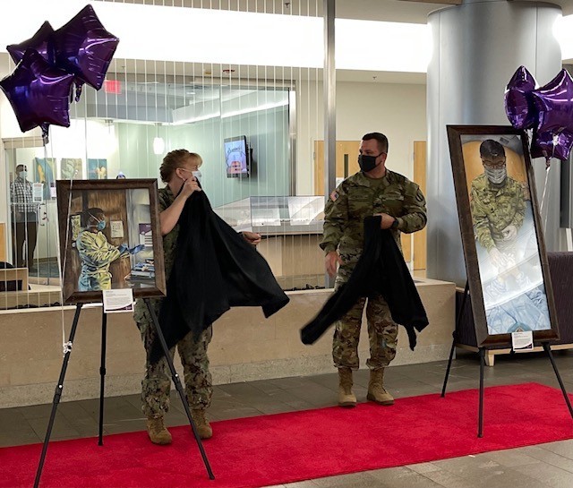 Navy Captain Cynthia Judy and Army Sgt. 1st Class Curt Loter unveil the artwork at the Fort Belvoir Community Hospital on August 4, 2021.