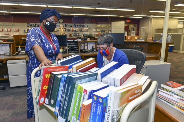 Jodi Quesnell, Director, Stimson Library (right) and Lakeitra Spight, Library Technician, look through a cart of books before placing them on the shelves.
