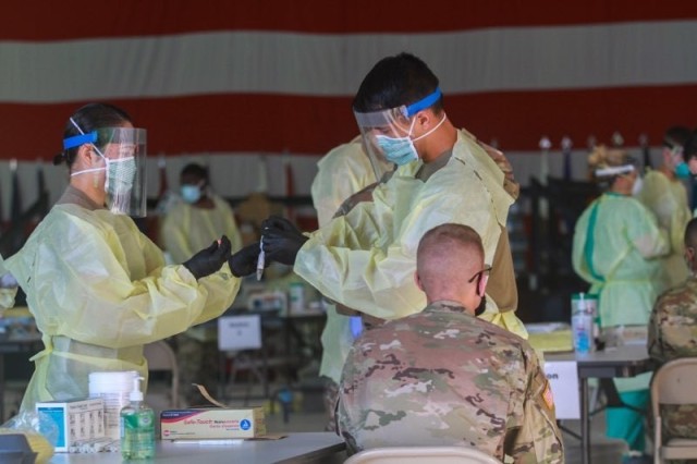 Specialist Hanul Yi, left, receives a sample for COVID-19 pool testing from Cpl. Evan Scott at Hangar 3, Aug. 23, 2020. Both Soldiers are medics assigned to A Company, 1st Battalion, 327th Infantry Regiment, 1st Brigade Combat Team, 101st Airborne...
