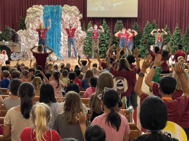 Children and staff lift their hands while the praise team leads the audience in a song and dance during day one of Humphreys Vacation Bible School, Aug. 9, at the Four Chaplains Memorial Chapel.  (Photo by Monica K. Guthrie)