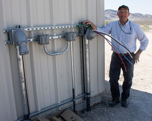 Nathan Lee, physical scientist for the upgrade project, stands beside one of the four pedestals added to the exterior of the Staging Facility. Each pedestal will power two trailers; up to eight external customer trailers may be accommodated during testing. If more power is needed, a mobile generator can be hooked up to the building. Photo by Al Vogel, Dugway Public Affairs
