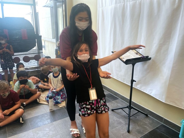 Charleigh Haller throws her arms out and falls backwards into the arms of Hannah Ahn, a volunteer at the Camp Humphreys Vacation Bible School, Aug. 9, at the Four Chaplains Memorial Chapel. (Photo by Monica K. Guthrie)