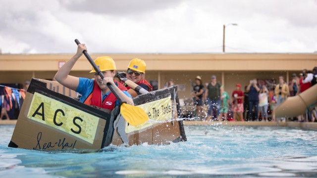 The Army Community Service boat hits the water during the Cardboard Regatta at Fort Bliss, Texas, Aug. 14, 2021. Bliss Family and Morale, Welfare and Recreation held the annual event, which challenged contestants to build two-person vessels out of corrugated cardboard and tape and keep them afloat during racing at the Community Pool on west Bliss. As the last race of the day, FMWR had an inter-directorate race finale.