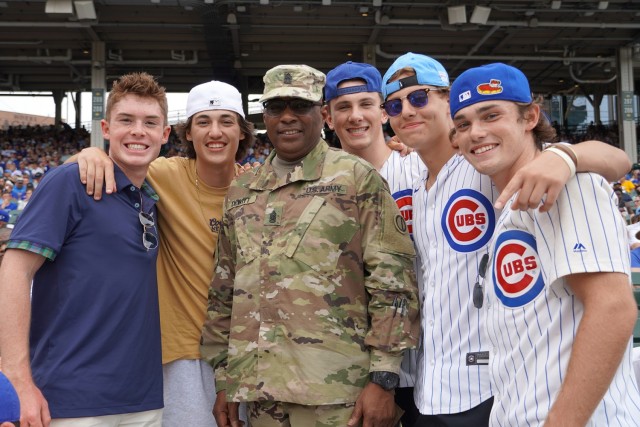 U.S. Army Reserve Command Sgt. Maj Theodore Dewitt, center, pauses for a photo with game spectators after receiving an honor for his service during the Chicago Cubs home game, at Wrigley Field in Chicago, August 12, 2021. Dewitt was honored during the game for his 36 years of service in the Army to include deployments to Kuwait, Iraq and Afghanistan. 
(U.S. Army Reserve photo by Capt. Michael J. Ariola)
