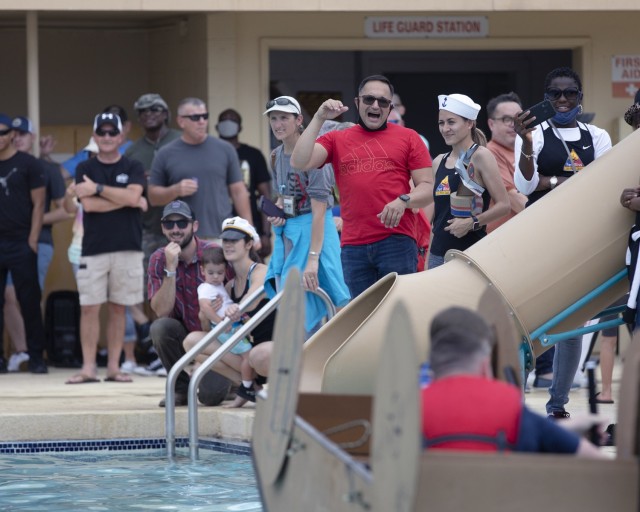 Well-wishers cheer at the Cardboard Regatta at Fort Bliss, Texas, Aug. 14, 2021. Bliss Family and Morale, Welfare and Recreation held the annual event, which challenged contestants to build two-person vessels out of corrugated cardboard and tape and keep them afloat during racing at the Community Pool on west Bliss. “This really encompasses ‘family, morale, welfare and recreation,’  because, we know that for at least a month prior, for some of these people, they were working on their boats as a family,” said Michele Wiernicki, the Bliss FMWR marketing director and the day’s emcee.