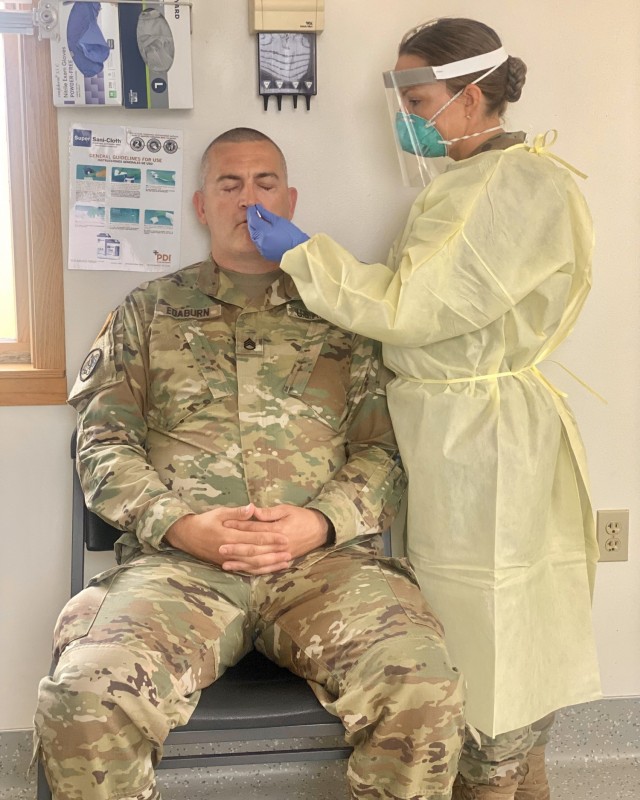 Capt. Elizabeth Babcock, Blanchfield Army Community Hospital medical laboratory manager, demonstrates how to perform a COVID-19 swab on Staff Sgt. Sean Edaburn, 7404th Troop Medical Command non-commissioned officer in charge, at the Fort McCoy...