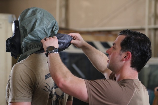 U.S. Navy Senior Chief Explosive Ordnance Disposal Technician Chris McGroew, CBRN Assessment and Response Team, CENTCOM-Enabling Support Package, demonstrates procedure for safely removing a chemical protective mask and hood to Soldiers with the 434th Chemical Company, 1st Battalion, 194th Armor Regiment, Task Force Bastard, during joint interoperability training August 12, 2021 at Camp Arifjan, Kuwait. (U.S. Army photo by Staff Sgt. Marc Heaton, Task Force Spartan Public Affairs)