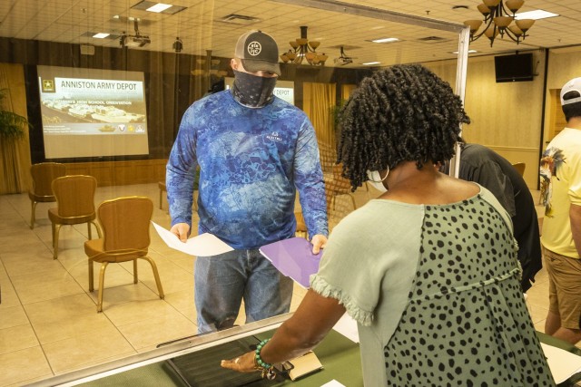 The pathways program assistant, Tuquita James, receives in-processing documentation at Anniston Army Depot from one of the students Aug. 5.
