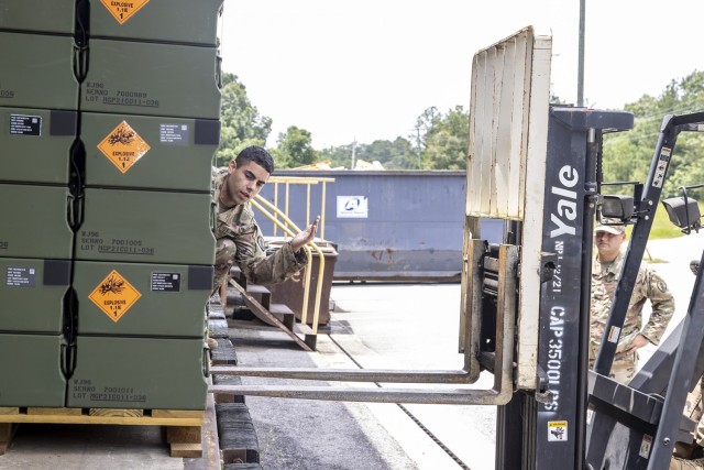 Sgt. Enrique Rosadomontero of the 266th Ordnance Company spots a forklift driver approaching palletized munitions.