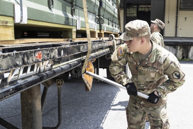 Spc. Baldy Fonrodonaaubert tightens a trailer winch strap to secure munitions cargo for transport.