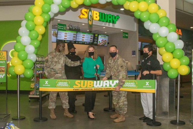 Fort Jackson Garrison Command Sgt. Maj. Algrish Williams, left, Exchange General Manager Kimberly Neiss, center, Garrison Commander Col. Ryan Hanson and Subway and Exchange staff cut a banner officially opening Subway on Aug. 17, 2021. After...