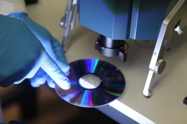 A fingerprint is placed on a CD and positioned under the PCFIS to demonstrate its ability to detect chemical residue left behind on the object.