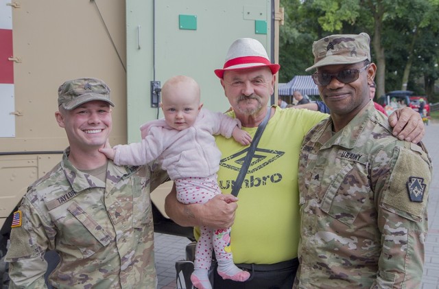 U.S. Army Sgt. Bradley Taylor (left) and U.S. Army Sgt. Emmanuel Biney-Anim interact with local residents during a static display at “Powidz Days,” a community arts and crafts event in Powidz, Poland, July 10, 2021. Taylor and Biney-Anim are...