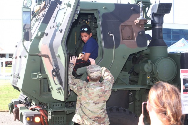 Sgt. 1st Class Zach Barner, talks with a boy about the High Mobility Artillery Rocket System he’s sitting in during the USO Experience Aug. 22, in Oklahoma City. Barner is a a field artillery instructor assigned to 1st Battalion, 78th FA, at Fort Sill, Oklahoma. 