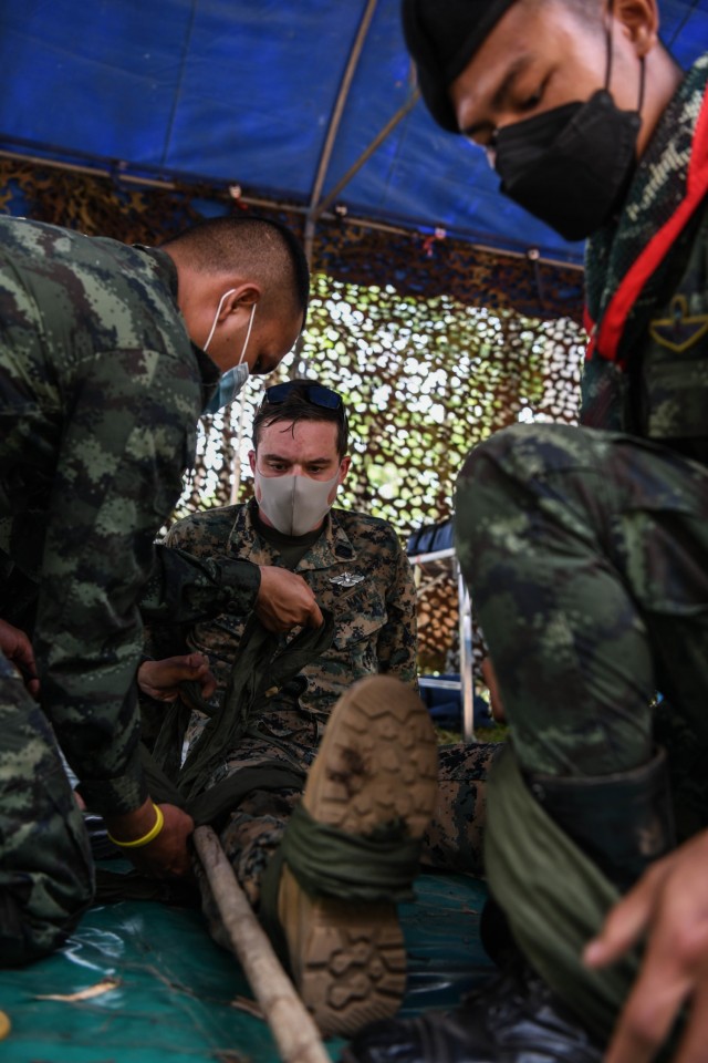 U.S. Navy Petty Officer 1st Class Philip Tockweiler, a corpsman with Headquarters and Support Company, 9th Engineer Support Battalion, 3rd Marine Logistics Group, checks the work of  Royal Thai Army Corporal Arnon Lolaem, right, a corpsman from Royal Thai Army Border Patrol Task Force 2, as they build and apply an improvised emergency traction splint using materials in the environment during Exercise Cobra Gold 21 at Ta Mor Roi training area in Surin Province, Thailand, August 7, 2021. Royal Thai and American Armed Forces worked together during the exercise to conduct landmine disposal operations, render-safe procedure training, and partnered medical response trauma training. This exercise is aligned with the U.S. Department of Defense’s Humanitarian Mine Action Program, which assists partnered nations affected by landmines, explosive remnants of war, and the hazardous effects of unexploded ordnance. (U.S. Marine Corps photo by Sgt. Carla O)