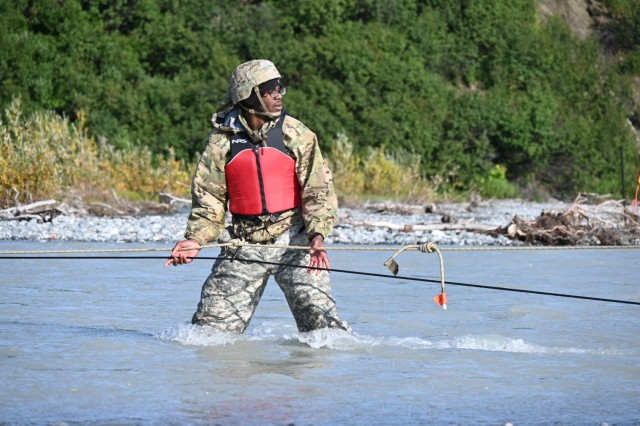 Spc. Earsey Toney crosses Phelan Creek in central Alaska on August 18 during the Basic Military Mountaineering Course conducted at the Black Rapids Training Site of the Northern Warfare Training Center. The source of the creek is Gulkana Glacier, and the water temperature was approximately 38 degrees Fahrenheit. The river crossing was the final event of the 15-day course. (Photo by Eve Baker, Fort Wainwright Public Affairs Office)