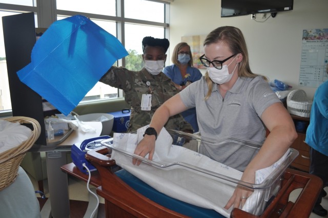 Martin Army Community Hospital Mother-Baby Unit CNOIC Capt. Katherine Basquill-White and Labor and Delivery Unit CNOIC Capt. Decilia Neely assemble the CuddleCot.