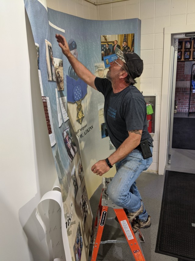 Jeff Fox, the illustrator/graphic designer from Fort Drum Public Works’ Signs and Graphics Section, spent several weeks last year designing and constructing a Medal of Honor wall display in honor of Staff Sgt. Travis Atkins, the 2nd Brigade Combat Team Soldier who was posthumously awarded the Medal of Honor in March 2019. He finished the project in late May, but the COVID-19 pandemic delayed the official rededication ceremony at Atkins Functional Fitness Facility and the display unveiling until Sept. 1. (Photo by Mike Strasser, Fort Drum Garrison Public Affairs)