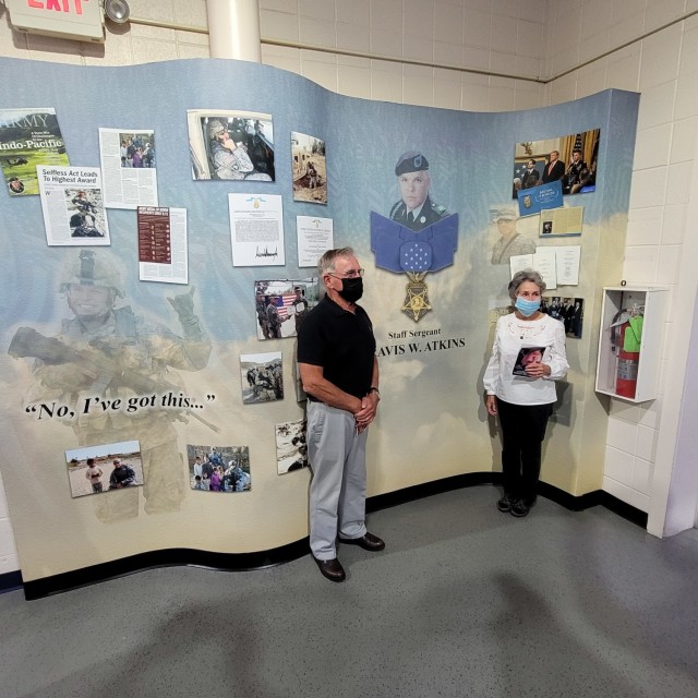 Jack and Elaine Atkins stand in front of the memorial display of their son, Staff Sgt. Travis Atkins, after the rededication ceremony Aug. 31 for the Atkins Functional Fitness Facility. (Photo by Mike Strasser, Fort Drum Garrison Public Affairs)