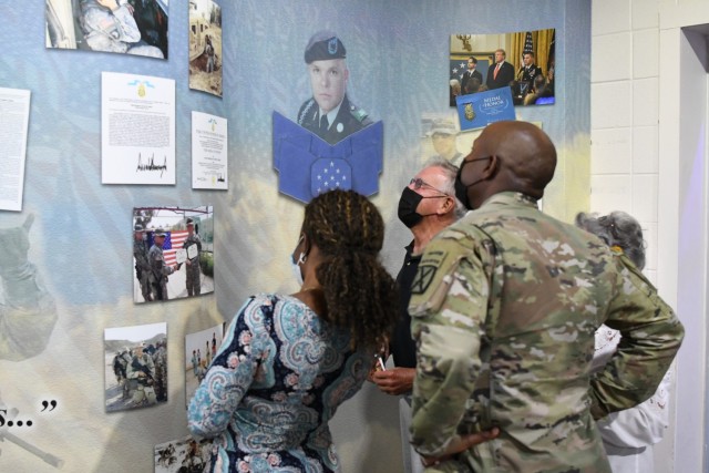 Col. Damon Harris, 2nd Brigade Combat Team commander, and his wife join Jack and Elaine Atkins in viewing the new memorial display for Staff Sgt. Travis Atkins inside Atkins Functional Fitness Facility on Aug. 31, after the rededication ceremony. (Photo by Mike Strasser, Fort Drum Garrison Public Affairs)
