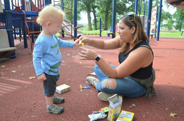 Abby Gripp, facilitator for the Rock Island Arsenal Discovery Playgroup, helps Wesley Patera create a sand art project. The Army Community Service playgroups are designed to develop social, emotional, and physical skills to build a strong...