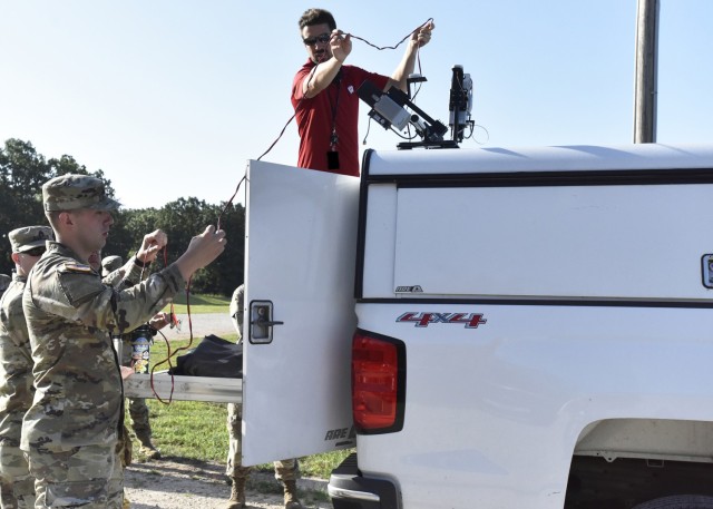 Casey Shanks from the National Geospatial-Intelligence Agency, or NGA, research team in St. Louis, Missouri, speaks with U.S. Army Training and Doctrine Command Proponent Office – Geospatial, or TPO-GEO, service members while setting up truck-mounted Lidar survey data collection sensors Aug. 23 at Range 24. Lidar – short for light detection and ranging – is a technology the Army is considering using to augment its ability to create high-resolution, or survey grade, 3-D maps.