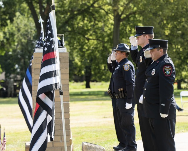 Local firefighters and police officers salute after placing their headgear and flags on each pillar of the 9/11 Memorial during a remembrance ceremony held at Rock Island Arsenal Sept. 10.