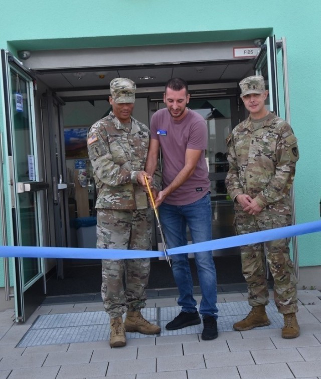 Col. Mario Washington, Wiesbaden Garrison Commander, and Sedat Selmani, an employee of the MWR outdoor recreation facility, cuts the ribbon to officially on the facility Sept. 7, 2021 as Command Sgt. Maj. Richard Russell looks on..