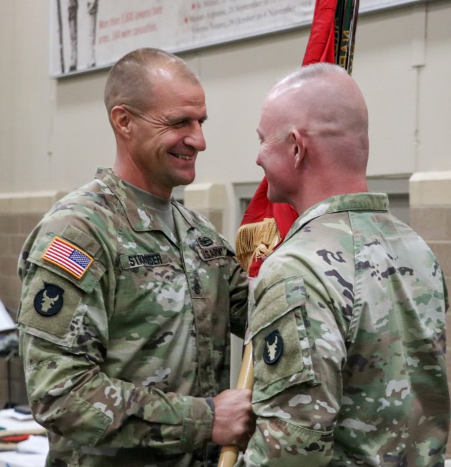 Command Sgt. Maj. Matthew Strasser, the outgoing senior enlisted leader of the 2nd Infantry Brigade Combat Team, 34th Infantry Division, Iowa Army National Guard, passes the unit colors to Col. Derek Adams, the brigade commander, during the change...