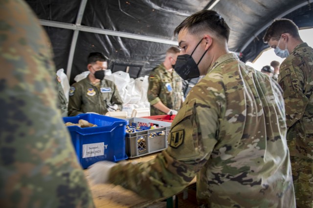 Service members from the U.S. Army and Air Force work shoulder to shoulder with soldiers from the German Bundeswehr to prepare meals for the Afghanistan evacuees. Ramstein Air Base is a transit center that provides a safe place for the evacuees to complete their paperwork while security and background checks are conducted before they continue on to their final destination. (U.S. Army photo by Staff Sgt. Thomas Mort)