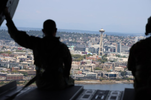 A member of the Royal Thai Army sits on the ramp of a CH-47 Chinook helicopter as it flies above Seattle, Aug. 25, 2021. The Thai Army aviators were taking part in a three-week aviation exchange with members of the Washington National Guard's...