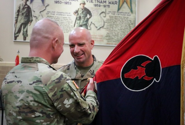 Command Sgt. Maj. Jeremy Strasser, the incoming senior enlisted leader of the 2nd Infantry Brigade Combat Team, 34th Infantry Division, Iowa Army National Guard, receives the unit colors from Col. Derek Adams, the brigade commander, during the...