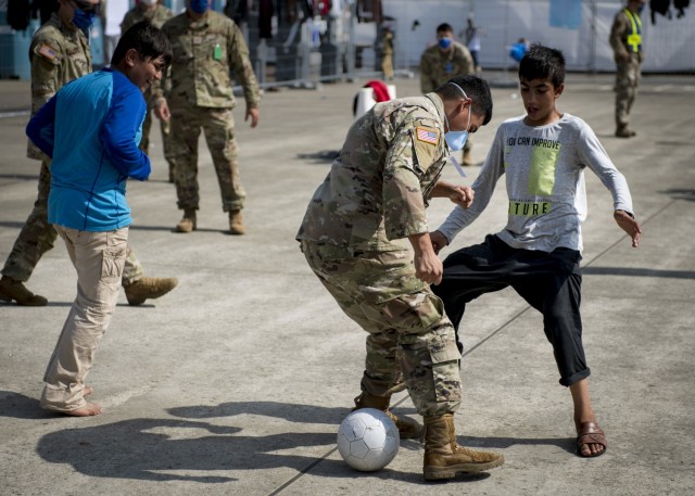 Soldiers assigned to the 1st Battalion, 6th Field Artillery Regiment, 41st Field Artillery Brigade play soccer with children from Afghanistan during Operation Allies Refuge at Ramstein Air Base, Germany, Sept. 10, 2021. Ramstein Air Base is a transit center that provides a safe place for the evacuees to complete their paperwork while security and background checks are conducted before they continue on to their final destination. (U.S. Army photo by Staff Sgt. Thomas Mort)