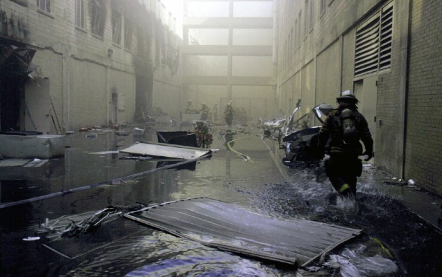 A Military District of Washington (MDW) Engineer Company (Technical Rescue) firefighter makes his way towards the fire on the second day after the attack. The morning before, in an attempt to frighten the American people, five members of Al-Qaida, a terrorist group of fundamentalist Muslims, hijacked American Airlines Flight 77, then flew a circuitous route returning to Washington and impacting the Pentagon killing all 64 passengers onboard and 125 people on the ground. The impact destroyed or damaged four of the five rings in that section of the building. Firefighters fought the fire through the night. (Photo courtesy of National Archives)